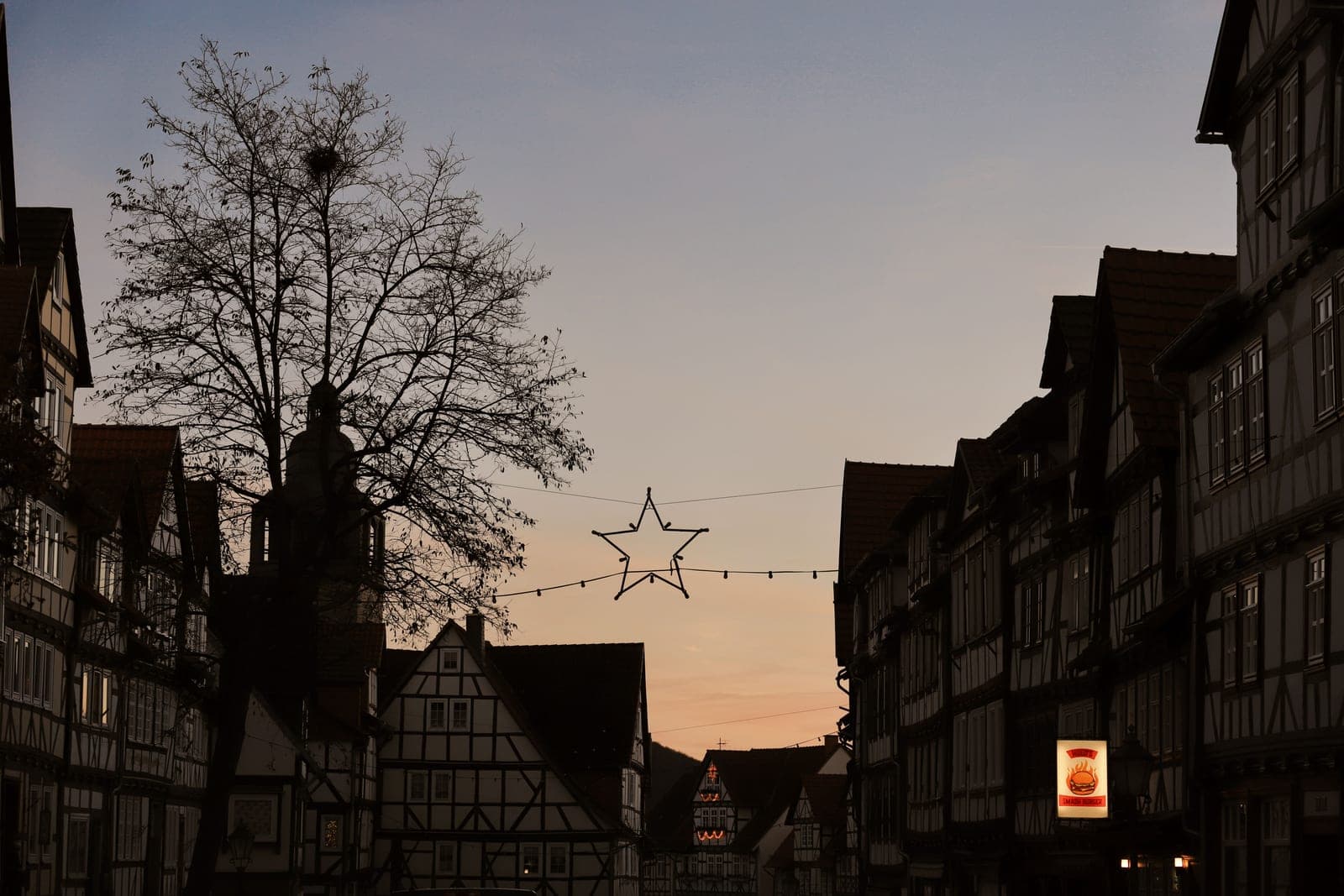 A house with its roofline and shrubs lit at dusk in December