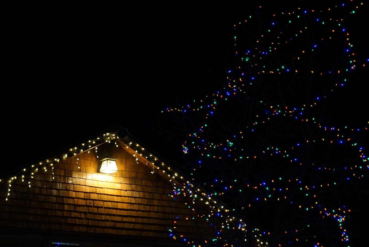 A house with its roofline outlined in Christmas lights